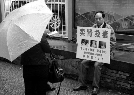 男子雨中举牌卖肾救妻 称妻子遭逼债已自杀多次